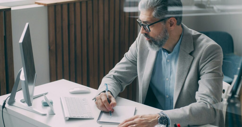 a man sitting down at a desk writing on a piece of paper