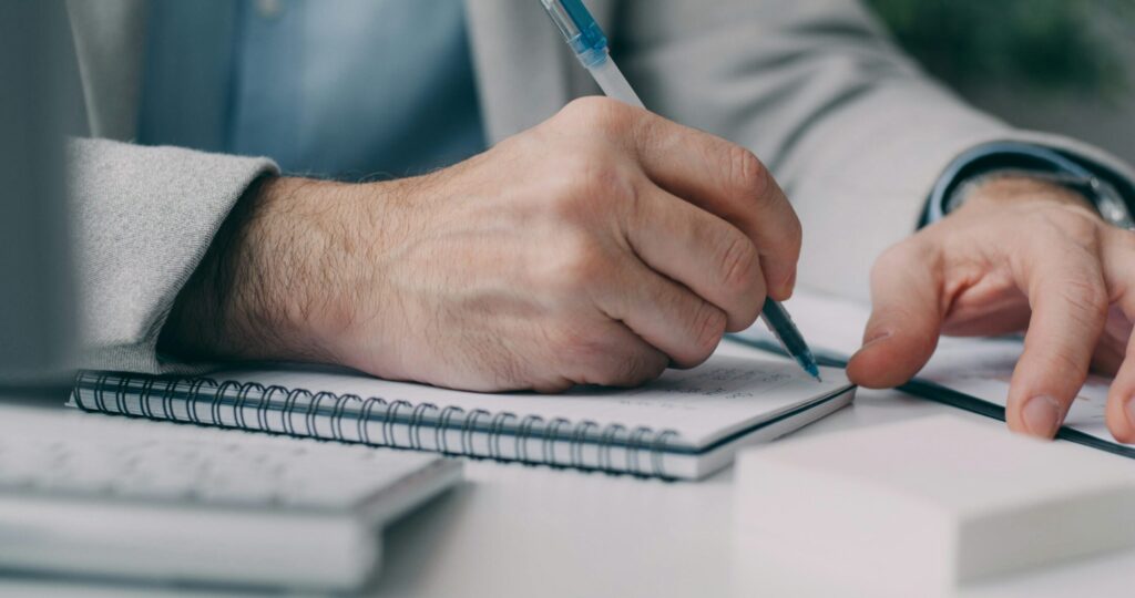 a man in a suit writing on a notebook